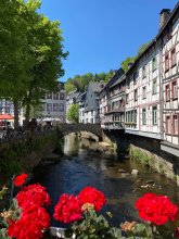 Marktplatz Monschau Auf dem Bild sieht man links den Marktplatz der Monschauer Altstadt, mittig eine Brücke und den darunter verlaufenden Bach und rechts eine Reihe von Fachwerkhäusern.