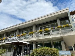 Rathaus Das Bild zeigt das Monschauer Rathaus. Ein großes Gebäude mit heller Fassade und Blumen in den Kästen auf dem Balkon.