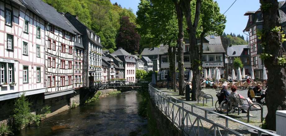 Das Bild zeigt weiße Häuser und einen Bach in der Altstadt von Monschau